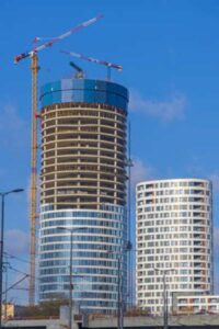 A circular building being constructed with cranes